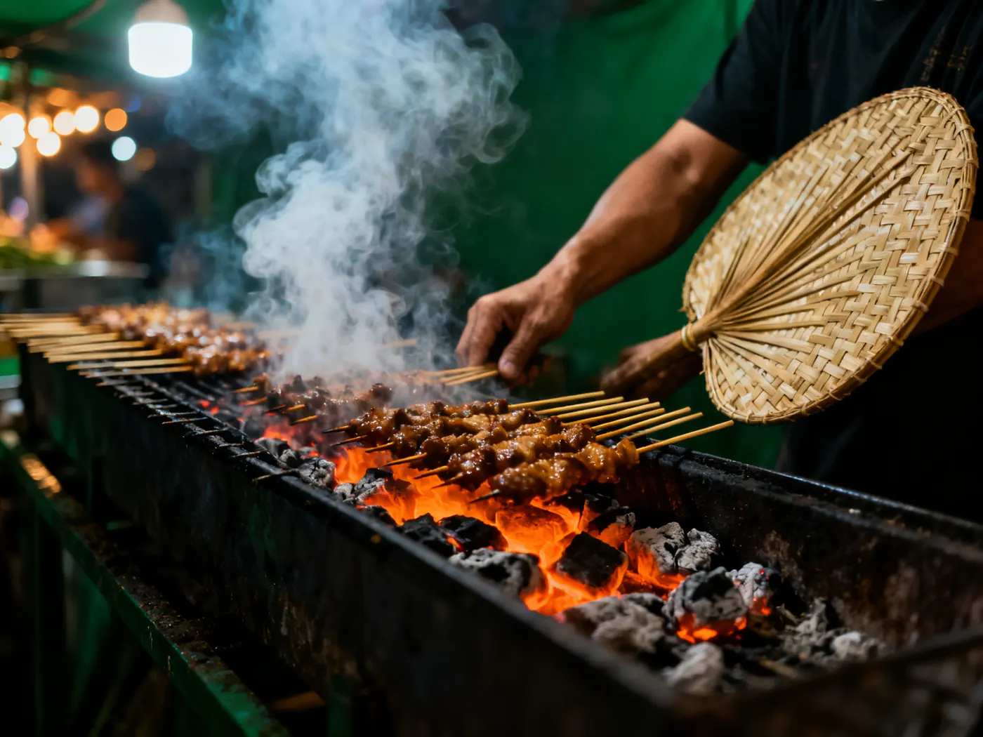 Sate dibakar di atas arang, dikipas dengan kipas bambu